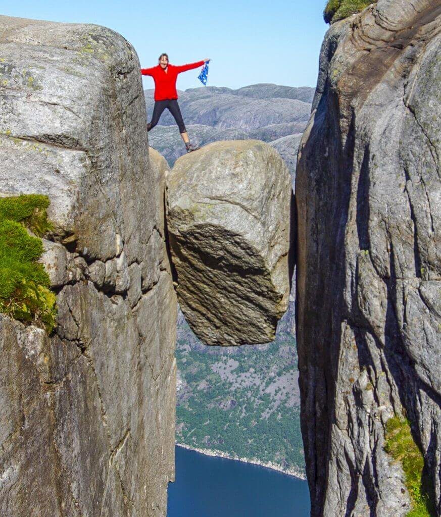 Top 5 Der besten Wandertouren in Norwegen Ein Mann, der auf dem Keil von Kjeragbolten besten Wanderungen in Norway steht